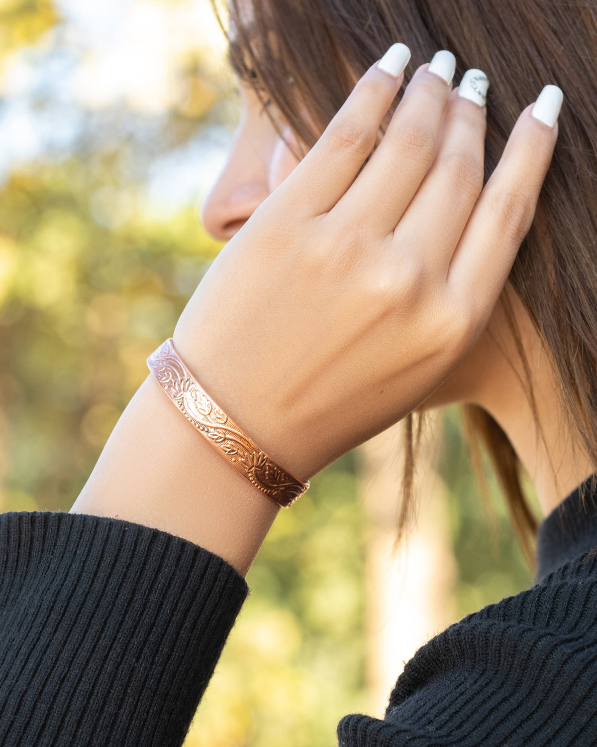 Person wearing a copper floral bracelet Blu Onyx